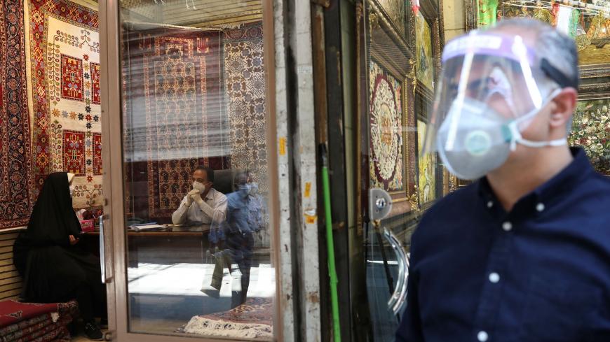 A carpet seller wears a protective face mask as he talks to a customer, following the outbreak of the coronavirus disease (COVID-19), after shopping malls and bazaars reopened in Tehran, Iran, April 20, 2020. WANA (West Asia News Agency)/Ali Khara via REUTERS ATTENTION EDITORS - THIS PICTURE WAS PROVIDED BY A THIRD PARTY - RC2E8G9PKEW3