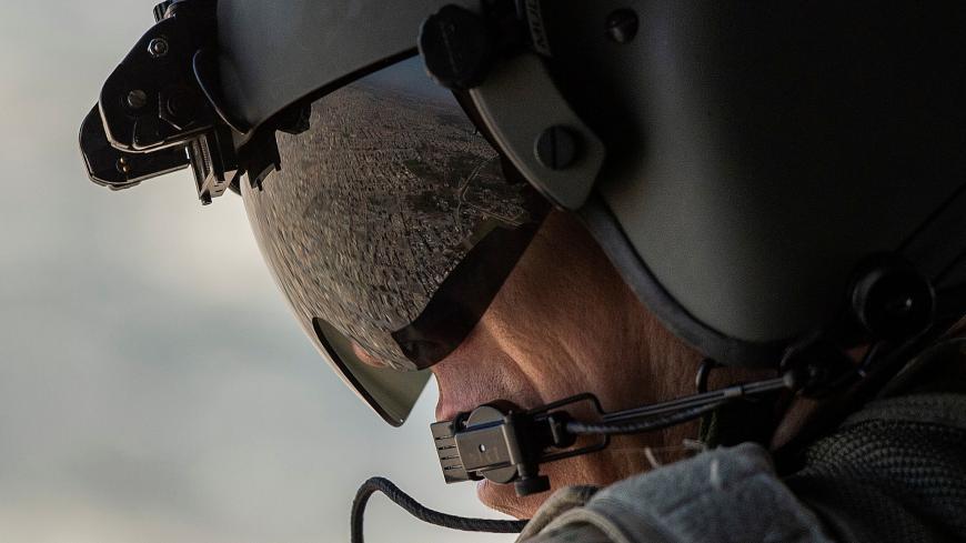 A partial view of the Iraqi capital Baghdad is reflected in the visor of a U.S. Army helicopter crew member as he looks out of a Chinook helicopter flying from the U.S. Embassy to Baghdad International airport, following the helicopter of U.S. secretary of State Mike Pompeo, in Iraq, January 9, 2019.  Andrew Caballero-Reynolds/Pool via REUTERS - RC1A9F707880