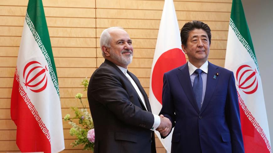 Iranian Foreign Minister Mohammad Javad Zarif, left, and Japanese Prime Minister Shinzo Abe, right, shake hands at Abe's official residence in Tokyo Thursday, May 16, 2019. Eugene Hoshiko/Pool via REUTERS - RC114BAC3050