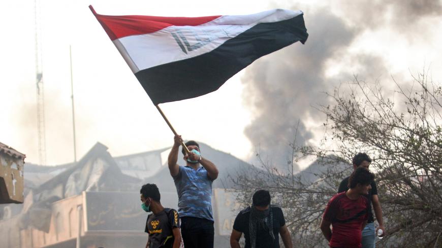 An Iraqi protester waves a national flag while demonstrating outside the burnt-down local government headquarters in the southern city of Basra on September 7, 2018 during demonstrations over poor public services. - Basra has seen a surge in protests since September 4, with demonstrators torching government buildings as well as political party and militia offices, as anger boils over after the hospitalisation of 30,000 people who had drunk polluted water. (Photo by Haidar MOHAMMED ALI / AFP)        (Photo c