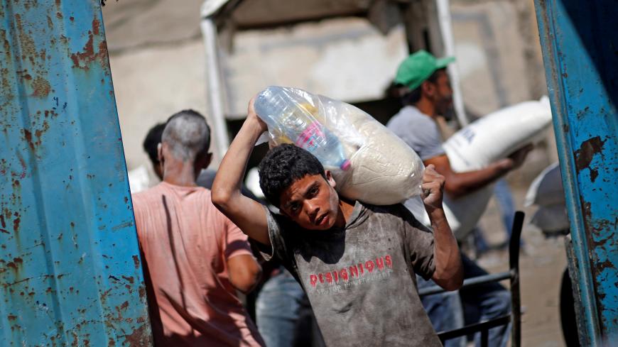 A Palestinian carries food supplies at an aid distribution center run by the United Nations Relief and Works Agency (UNRWA), in Al-Shati refugee camp in Gaza City September 25, 2019. REUTERS/Mohammed Salem - RC16E05A7E10