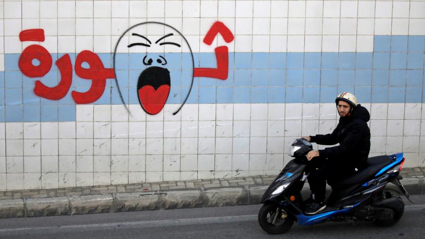 A man rides on a motorbike past graffiti which reads "Revolution", in Beirut, Lebanon, November 3, 2019.  REUTERS/Andres Martinez Casares - RC1830CECF20