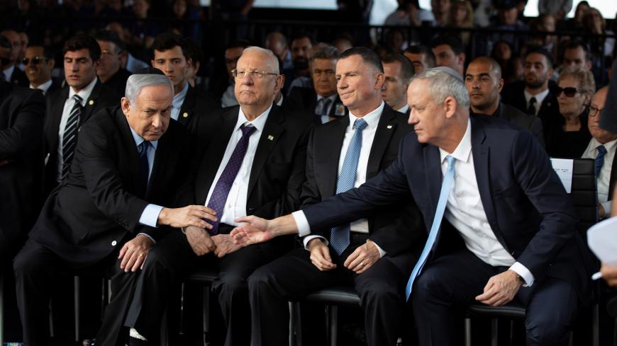 Head of Israel's Blue and White Party Benny Gantz and Israeli Prime Minister Benjamin Netanyahu shake hands as they attend a memorial ceremony for the late prime minister Yitzhak Rabin at Mount Herzl military cemetery in Jerusalem as Israel marks the 24th anniversary of Rabin's killing by an ultra-nationalist Jewish assassin, November 10, 2019. Heidi Levine/Pool via REUTERS - RC2G8D9LHA0U