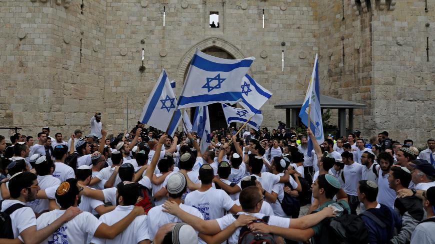 TOPSHOT - Israeli nationalist settlers wave their national flag as they celebrate the Jerusalem Day at the Old City's Damascus gate in Jerusalem on May 13, 2018. - For Israelis, Sunday is Jerusalem Day, an annual celebration of the "reunification" of the city following the 1967 Six-Day War. (Photo by MENAHEM KAHANA / AFP)        (Photo credit should read MENAHEM KAHANA/AFP via Getty Images)