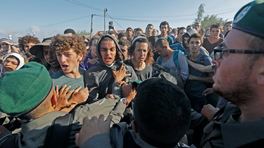 TOPSHOT - Israeli settlers scuffle with Israeli security forces at Netiv Haavot settlement, near Bethlehem, in the occupied West Bank on June 12, 2018. - Fifteen Israeli settler families are expected to evacuate their homes in this outpost after it was declared illegal by the Israeli High Court (Photo by Menahem KAHANA / AFP)        (Photo credit should read MENAHEM KAHANA/AFP via Getty Images)