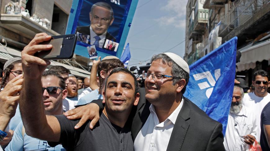 Leader of the far right 'Otzma Yehudit' (Jewish power) party Itamar Ben-Gvir poses for a selfie with a supporter as he campaigns at the Mahane Yehuda Market in Jerusalem on September 13, 2019. (Photo by MENAHEM KAHANA / AFP)        (Photo credit should read MENAHEM KAHANA/AFP via Getty Images)