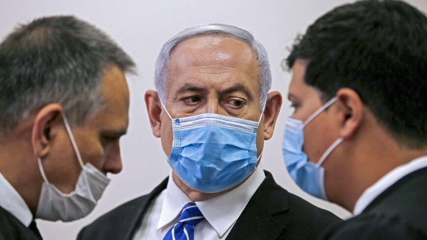 Israeli Prime Minister Benjamin Netanyahu (C), wearing a protective face maks, speaks with his lawyer inside a courtroom at the district court of Jerusalem on May 24, 2020, during the first day of his corruption trial. - Fresh from forming a new government after more than 500 days of electoral deadlock, Netanyahu is expected to begin a new battle in the Jerusalem District Court -- to stay out of prison. The 70-year-old was scheduled to appear at a court hearing to formally confirm his identity to judges, af