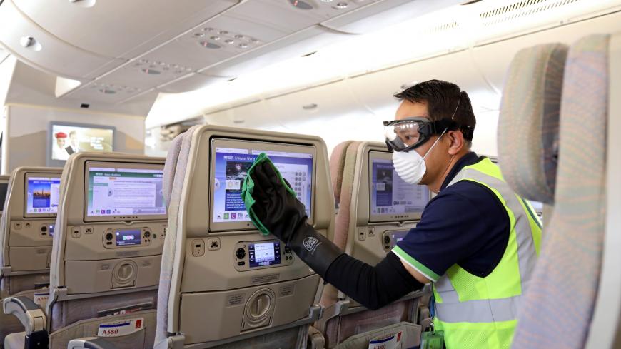 A member of cleaning staff wearing protective mask disinfects a seat screen of an Emirates Airbus A380, following the outbreak of the coronavirus, in Dubai, United Arab Emirates March 5, 2020. Picture taken March 5, 2020. Emirates Airline/Handout via REUTERS ATTENTION EDITORS - THIS PICTURE WAS PROVIDED BY A THIRD PARTY. - RC2WGF9HGKRA