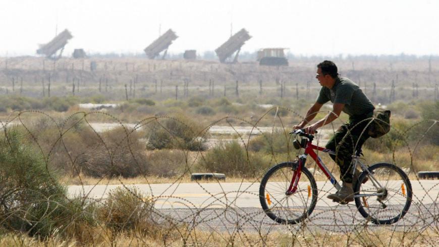 A British Royal Air Force Harrier GR7 groundcrew member cycles along the apron infront of a Patriot Missile defence system on his base in Kuwait April 6, 2003. [U.S. troops have a tight control on Baghdad airport and will move out from there in all directions, Jim Wilkinson, a spokesman for U.S. commander General Tommy Franks, said on Sunday.] - PBEAHUOQIBA