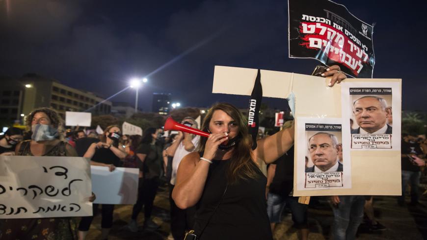 TEL AVIV, ISRAEL - JULY 11:  Israeli woman holds a sign with photos of Israeli Prime Minister Benjamin Netanyahu as she protests against the Government's economy response to the cororna virus crisis on July 11, 2020 in Tel Aviv, Israel. Following a rise in the cases of COVID-19, Israeli Prime Minister Benjamin Netanyahu has ordered many businesses to shut, causing people to protest about a perceived mishandling of the coronavirus pandemic and to call for the compensation promised by the government to be pai