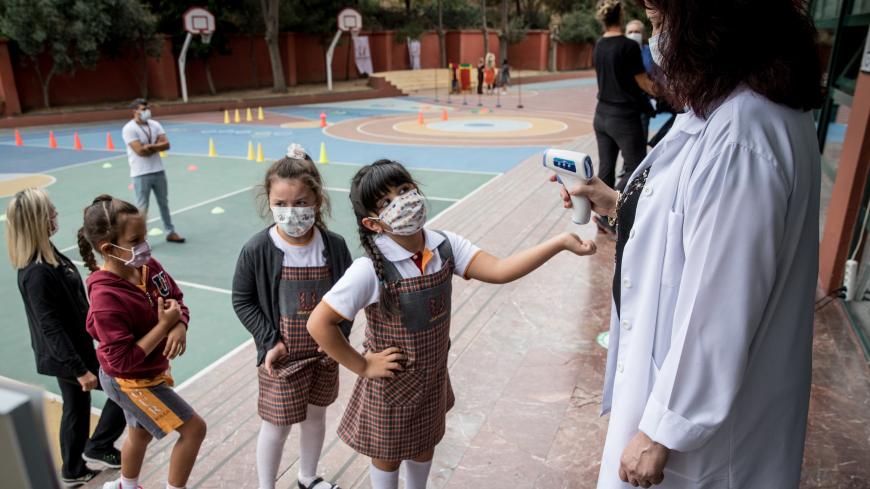 ISTANBUL, TURKEY - SEPTEMBER 21: First grade students wearing protective face masks line up to have their temperature taken before entering the school building at the Florya Ugur College on September 21, 2020 in Istanbul, Turkey. For the first time since schools closed on March 16, due to the coronavirus outbreak, kindergarten and first grade students were allowed to return for in-person classes at schools across Turkey. The one day a week classes are voluntary and restarted amid strict coronavirus precauti