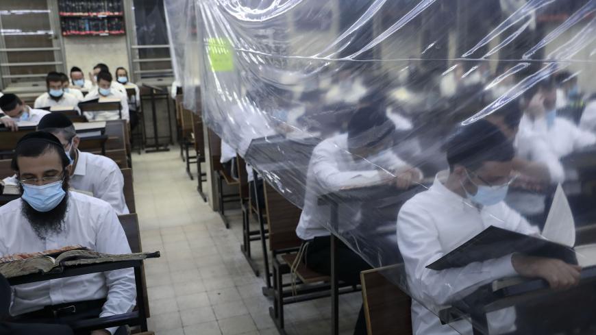 Ultra-Orthodox Jewish men study in a hall divided with plastic sheets as prevention from COVID-19, at their Kollel, a gathering place for full-time advanced Jewish law studies, in the religious city of Bnei Brak near Tel Aviv in central Israel, on October 25, 2020. - As Israel entered lockdown in March, a video emerged showing 92-year-old rabbi Chaim Kanievsky, one of the world's most powerful, flanked by his grandson and top advisor Yaakov, professing ignorance about coronavirus and insisting religious sch