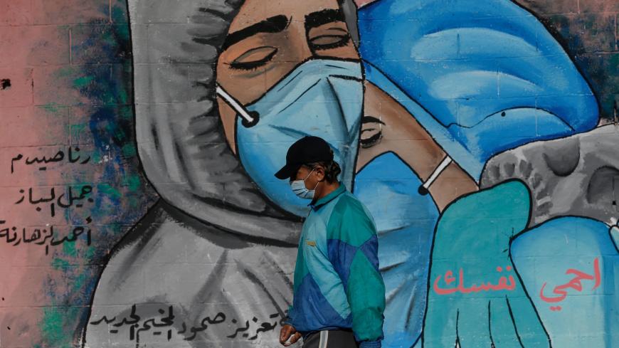 A Palestinian man walks past street art showing doctors mask-clad due to the COVID-19 coronavirus pandemic in the Nusseirat refugee camp in the central Gaza Strip on November 16, 2020. (Photo by MOHAMMED ABED / AFP) (Photo by MOHAMMED ABED/AFP via Getty Images)