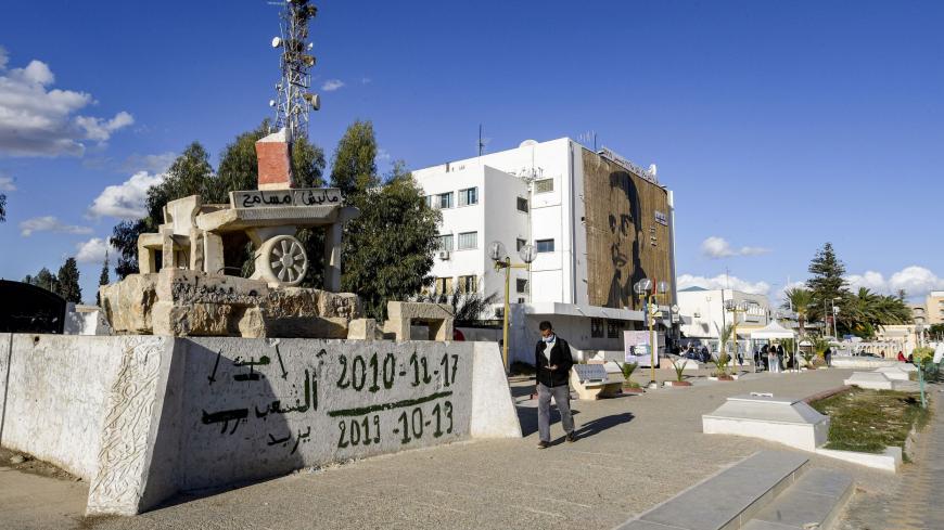 A man walks past a sculpture of Mohamed Bouazizi's cart (bearing text reading in Arabic: "I do not forgive") in the square named after him in the centre of the town of Sidi Bouzid in central Tunisia on October 27, 2020, the cradle of the 2011 Tunisian revolution where unemployment remains high ten years later. - The sister of Mohamed Bouazizi, whose self-immolation sparked a string of Arab uprisings, says she is "very disappointed" in Tunisia's revolution and has urged young Tunisians to continue the fight 