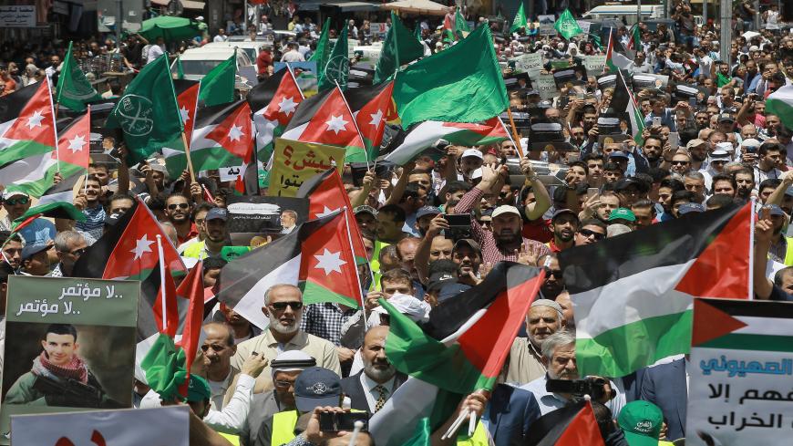 Flags of Jordan and the Muslim Brotherhood are waved with other protest signs denouncing the US-led Middle East economic conference in Bahrain, during a post-Friday prayers demonstration against US President Donald Trump's "Deal of the Century" in the Jordanian capital Amman on June 21, 2019. (Photo by Khalil MAZRAAWI / AFP)        (Photo credit should read KHALIL MAZRAAWI/AFP via Getty Images)