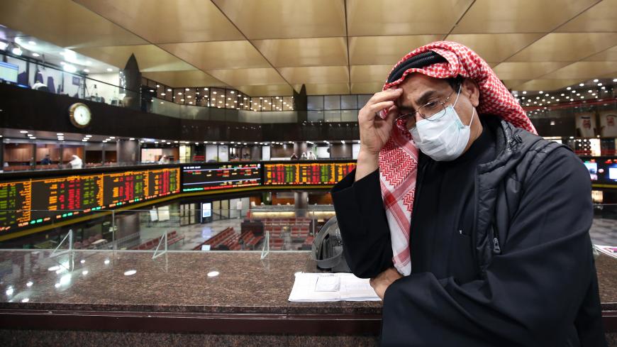 A Kuwaiti trader wearing a protective mask follows the market at the Boursa Kuwait stock exchange in Kuwait City on March 1, 2020. - Boursa Kuwait decided to close the main trading hall due to the COVID-19 coronavirus disease developments. Stock markets in the oil-rich Gulf states plunged on March 1 over fears of the impact of the coronavirus, which also battered global bourses last week. All of the seven exchanges in the Gulf Cooperation Council (GCC), which were closed the previous two days for the Muslim