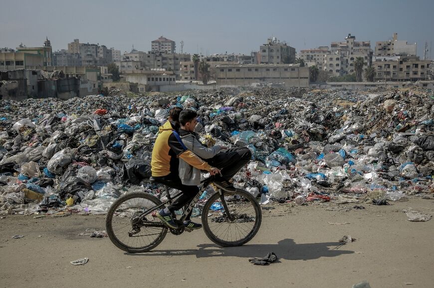 A Palestinian boy cycles past a huge garbage dump in Gaza City 