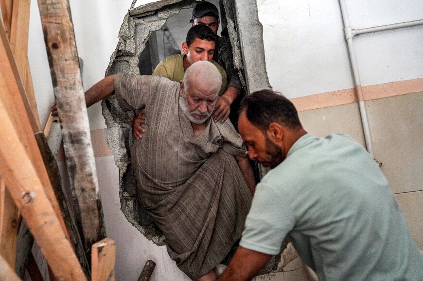 A man is helped to evacuate from a building in Nuseirat, central Gaza, after Israeli bombardment 