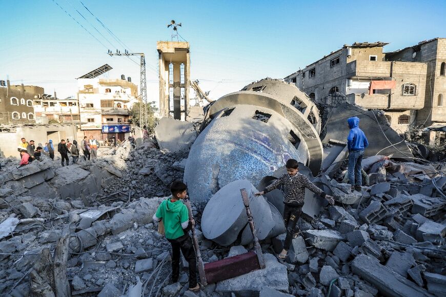 Children look for salvageable items amid the rubble of Al-Bukhari Mosque destroyed in Israeli strikes in Deir al-Balah in central Gaza on March 2, 2024.