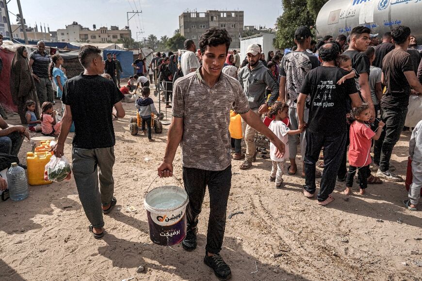 A youth strolls with a pail of water from a tanker tank in Deir el-Balah in the main Gaza Strip on April 30, 2024