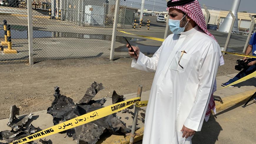 A man photographs debris from 2020 Houthi attack on a Saudi Aramco oil facility in Jeddah.