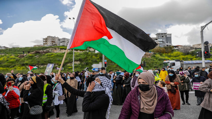 A demonstrator waves a Palestinian flag as Arab Israelis march during a demonstration in the mostly Arab city of Umm al-Fahm, against organized crime and calling upon the Israeli police to stop a wave of intracommunal violence, northern Israel, March 12, 2021.