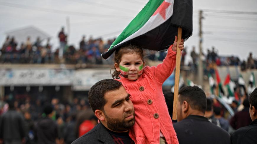 A girl holds a Syrian opposition flag during a demonstration in the village of Atme in Idlib.