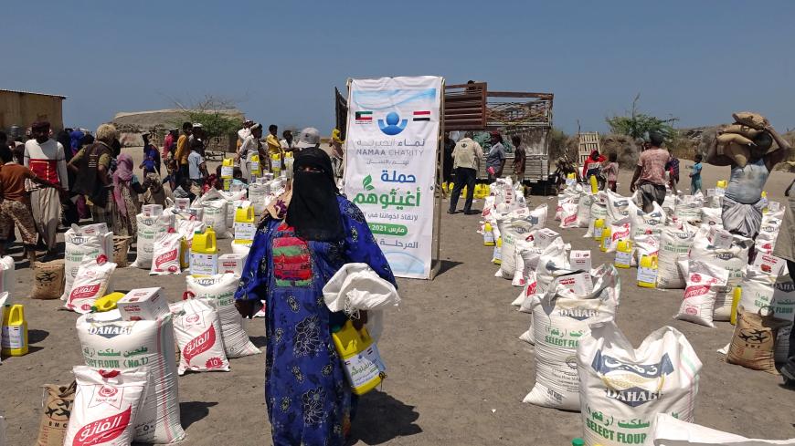 People displaced by conflict receive food aid donated by a Kuwaiti charity organisation in the village of al-Haima in the Khokha district of Yemen's war-ravaged western province of Hodeida, on March 20, 2021.