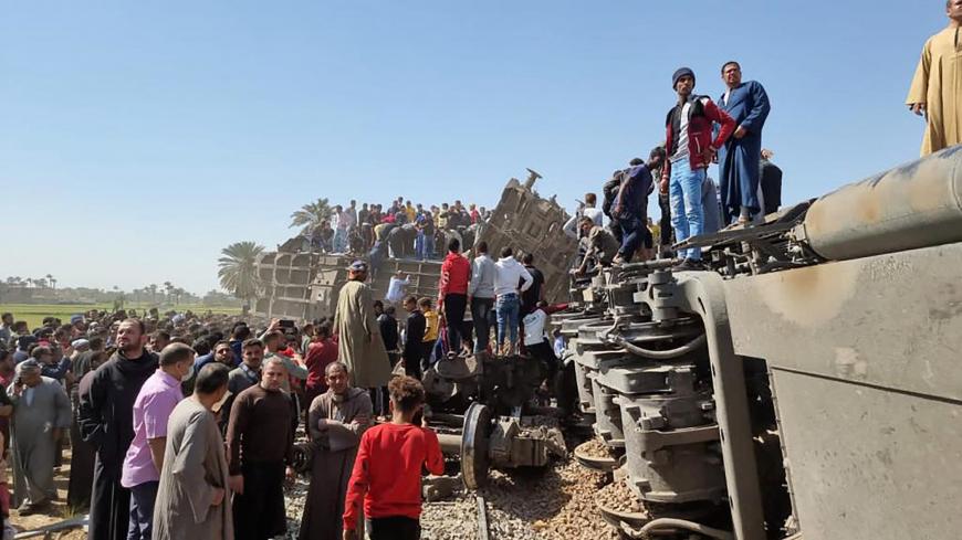 People gather around the wreckage of two trains that collided in the Tahta district of Sohag province, some 460 kms (285 miles) south of the Egyptian capital Cairo, reportedly killing at least 32 people and injuring scores of others, on March 26, 2021.