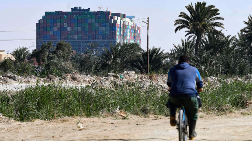 A man rides his bycycle in the northeastern Egyptian city of Ismailiya, in front of the Panama-flagged MV 'Ever Given' 