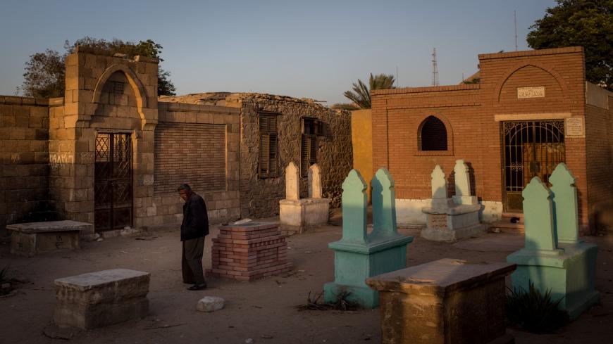 A man walks past tombstones in the poor neighborhood of the City of the Dead, which houses more than half a million people living inside the graveyard, Cairo, Egypt, Dec. 13, 2016.