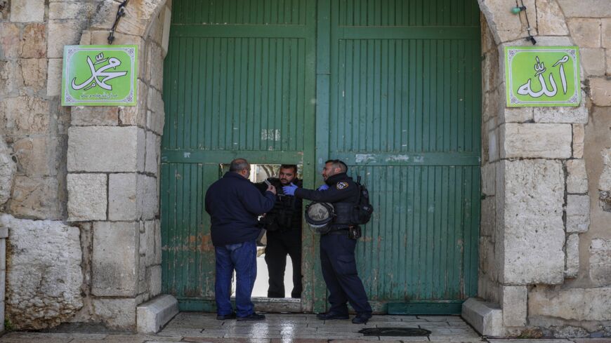 Israeli policemen check the ID of an employee before he enters Al-Aqsa Mosque compound in the Old City of Jerusalem on March 23, 2020, due to its closure following the Waqf decision in response to the coronavirus outbreak. 