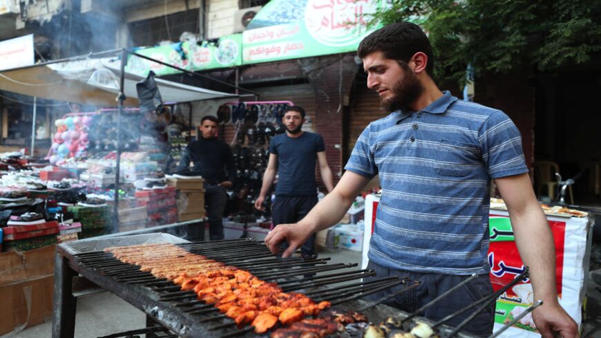 A man grills skewers outside a local restaurant along a market street in Ariha in the southern countryside of Syria's Idlib province before sunset during the Muslim holy fasting month of Ramadan on May 15, 2020, as people who had fled advancing government forces months earlier return to the town.