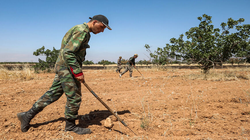 A Syrian army soldier uses a detector to find and clear landmines in a field at a pistachio orchard in the village of Maan, north of Hama, in west-central Syria, June 24, 2020.