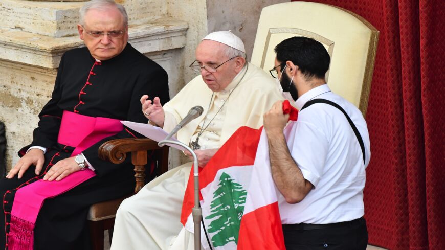 Pope Francis speaks about the situation in Lebanon as a Lebanese priest (R) holds Lebanon's flag and Monsignor Leonardo Sapienza (L) looks on during the pope's limited public audience at the San Damaso courtyard in The Vatican on Sept. 2, 2020. 