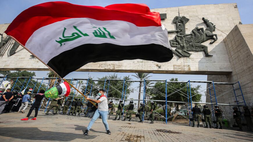 A demonstrator waves a large Iraqi national flag during an anti-government protest over corruption and poor services in Tahrir Square in the center of Iraq's capital, Baghdad, on Nov. 8, 2020. 