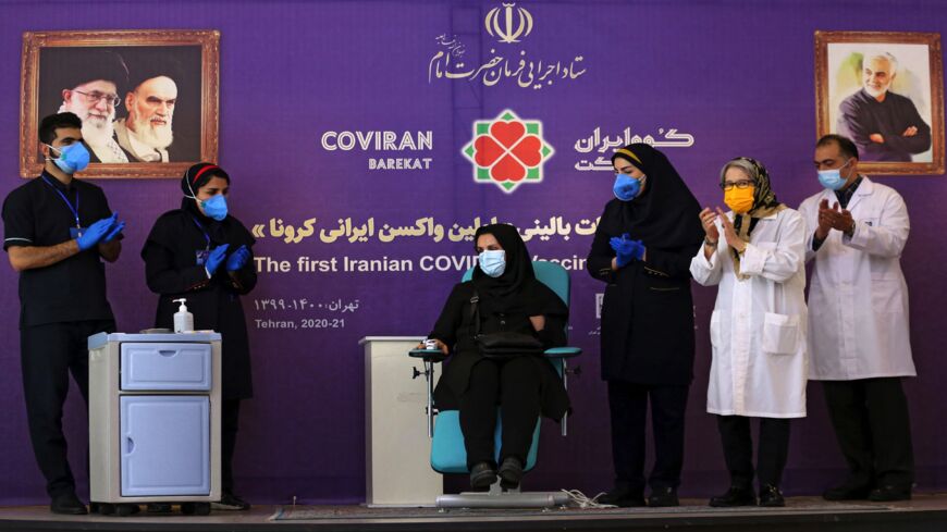 An Iranian health worker injects university professor Mahnaz Rasouli-Nejad with a dose of a locally made Iranian COVID-19 vaccine during the second phase of trials in the capital, Tehran, on March 15, 2021.