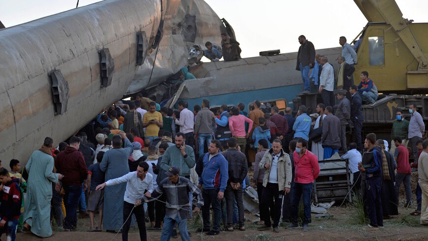 People gather around the wreckage of two trains that collided in the Tahta district of Sohag province, some 460 kilometers (285 miles) south of the Egyptian capital Cairo, reportedly killing at least 19 people and injuring scores of others, on March 26, 2021.
