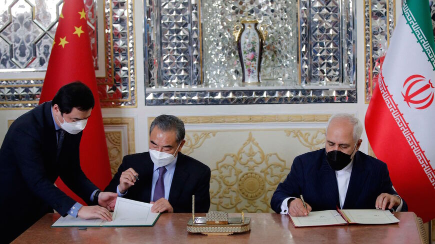 Iranian Foreign Minister Mohammad Javad Zarif (R) and his Chinese counterpart Wang Yi (C), sign an agreement in the capital Tehran, on March 27, 2021.