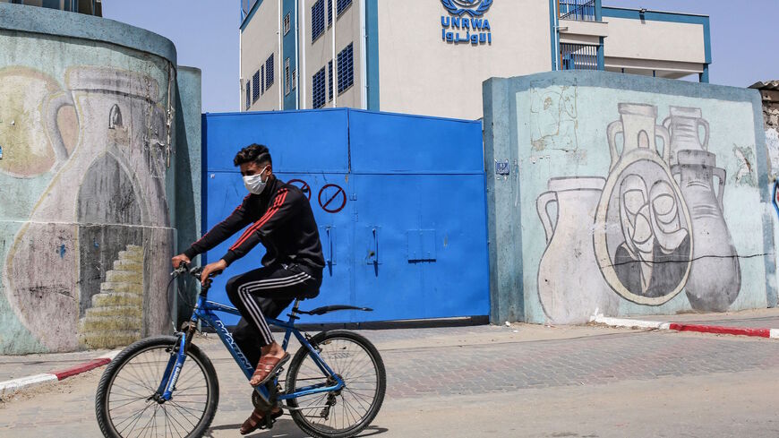 A Palestinian rides a bicycle past the closed gate of a school run by the United Nations Relief and Works Agency for Palestinian Refugees (UNRWA) in the city of Rafah in the southern Gaza Strip on April 6, 2021, amidst a lockdown due to the COVID-19 coronavirus pandemic. (Photo by SAID KHATIB / AFP) (Photo by SAID KHATIB/AFP via Getty Images)