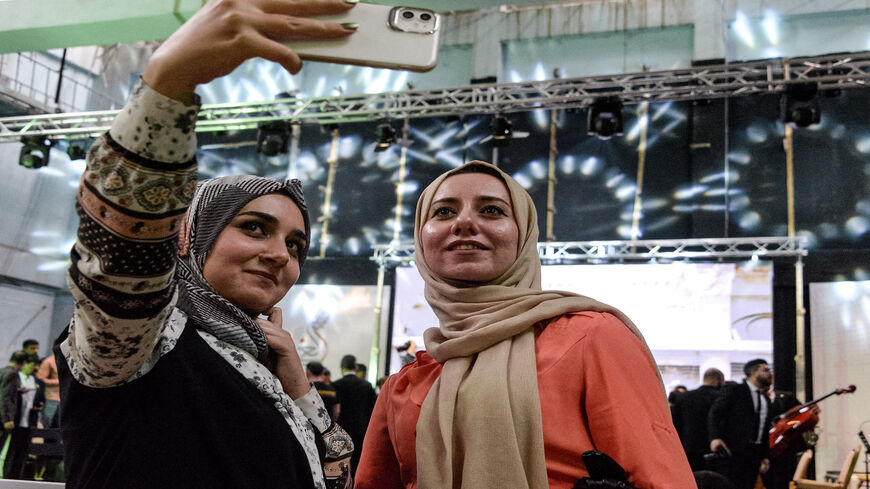 Women pose for a selfie after attending a performance by the Watar orchestral ensemble playing for the first time at the Spring Theater Hall, which was ravaged in the aftermath of the occupation by the Islamic State, Mosul, Iraq, April 8, 2021. 