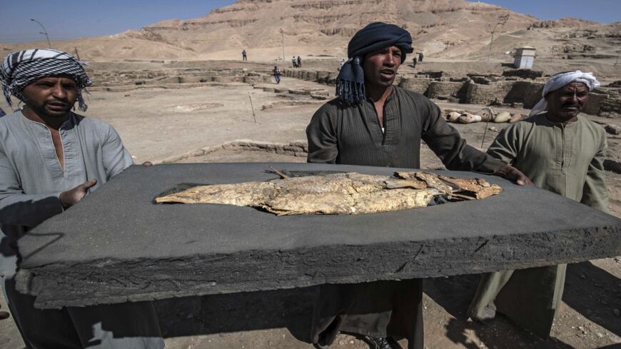 A picture taken on April 10, 2021, shows workers carrying a fish covered in gold uncovered at the archaeological site of a 3000-year-old city, dubbed The Rise of Aten, dating to the reign of Amenhotep III, uncovered by the Egyptian mission near Luxor.