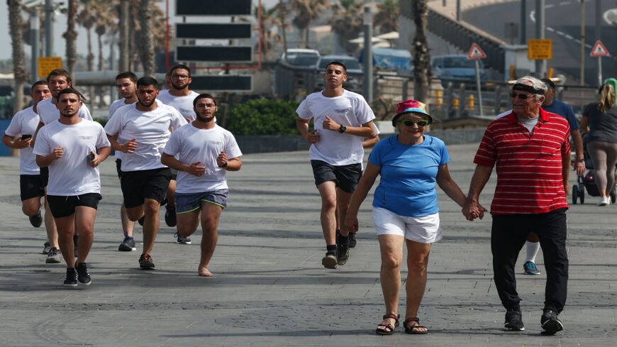 People exercise on a street in the Israeli coastal city of Tel Aviv on April 18, 2021, after authorities announced that face masks for COVID-19 prevention were no longer needed outside.