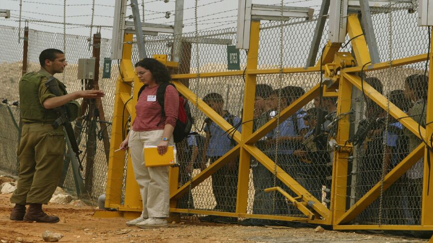 Israeli human rights activist Adi Dagan listens to an Israeli soldier as she waits for troops to allow Palestinian schoolchildren home through a gate in the security fence March 2, 2004, at the village of Jubara near the West Bank town of Tulkarem. The 300 Israeli women volunteers of the Machsom Watch group have appointed themselves to the task of monitoring the Israeli army, which operates about 65 manned and hundreds of unmanned checkpoints in the West Bank.