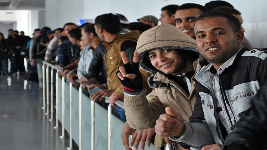 Egyptians, who were formerly residing in Libya, flash the sign for victory as they line up for checks by Tunisian customs at Djerba airport on the Tunisian-Libyan border, before being evacuated on a flight heading to Cairo, Egypt, Feb. 23, 2015.