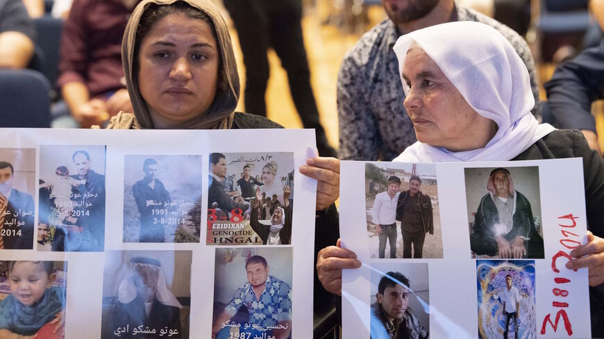 Yazidi women hold up pictures of missed relatives during a commemoration ceremony in Stuttgart, southern Germany, on Aug. 3, 2019. 