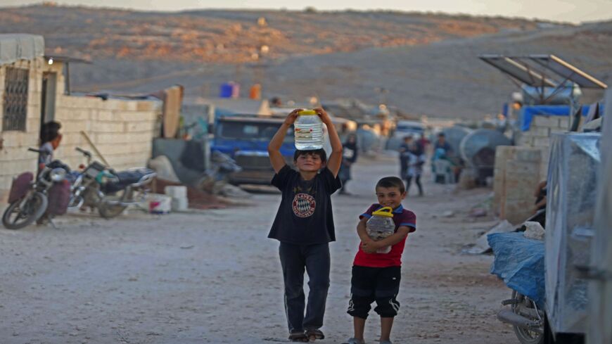 Displaced Syrian boys carry water back to their tent at a camp for the internally displaced near the town of Sarmada in Syria's northwestern Idlib province on July 29, 2020, as Muslims across the world are getting ready to celebrate Eid al-Adha.