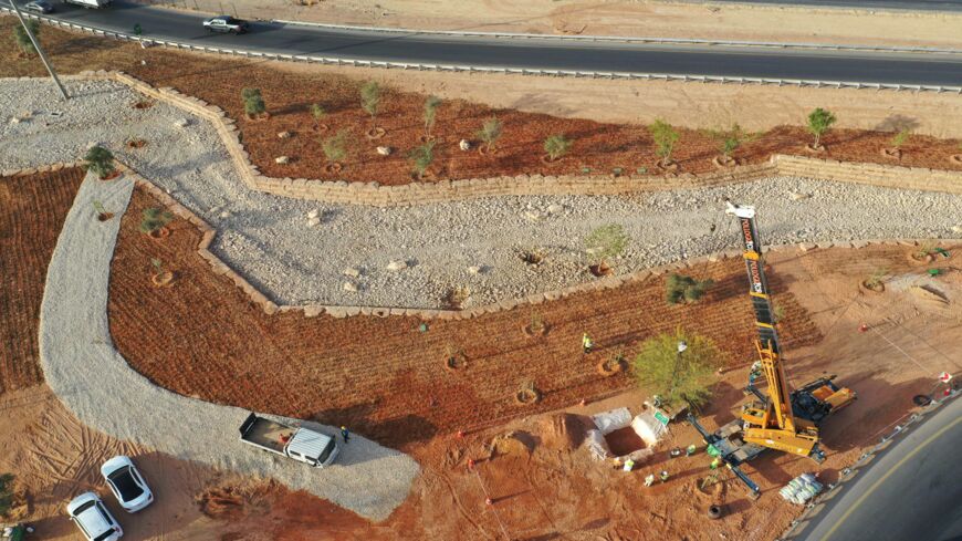 An aerial picture shows workers using a crane to plant trees in a park project by the roadside in the Saudi capital, Riyadh, on March 29, 2021. Although the OPEC kingpin seems an unlikely champion of clean energy, the "Saudi Green Initiative" aims to reduce emissions by generating half of its energy from renewables by 2030.