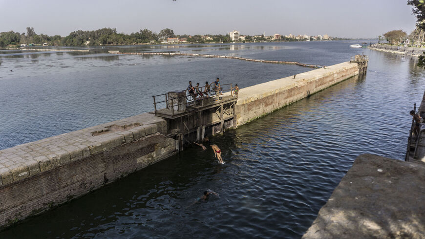 Youths dive into the water at the entrance of a canal near the Nile river delta barrages at the town of Qanater al-Khayreya north of the capital on May 3, 2021 during the holiday of Sham al-Nessim, a Pharaonic feast that marks the start of spring, which this year coincides with the Muslim holy fasting month of Ramadan.
