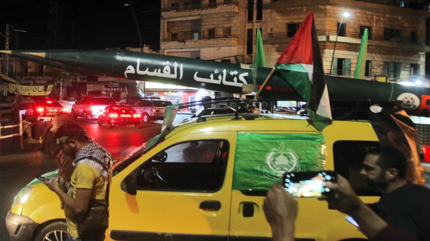 Men parade with a model of a rocket with "Qassam Brigades" (Hamas armed wing) written in Arabic, during a demonstration called by the Palestinian Islamist group Hamas in the southern Lebanese city of Saida late on May 11, 2021.